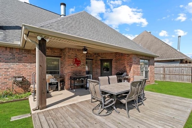 wooden deck featuring a grill, a ceiling fan, a lawn, outdoor dining space, and fence