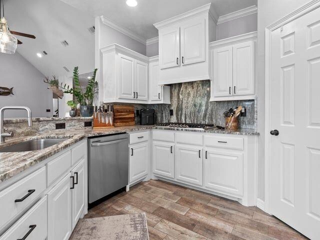 kitchen with tasteful backsplash, a ceiling fan, appliances with stainless steel finishes, light stone counters, and a sink