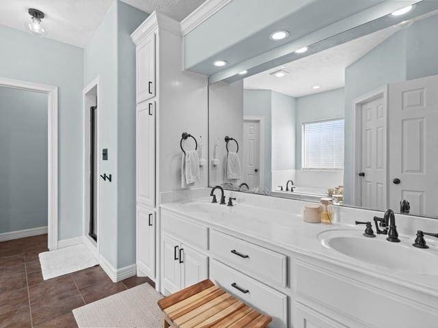 full bathroom with a sink, tile patterned floors, double vanity, and baseboards