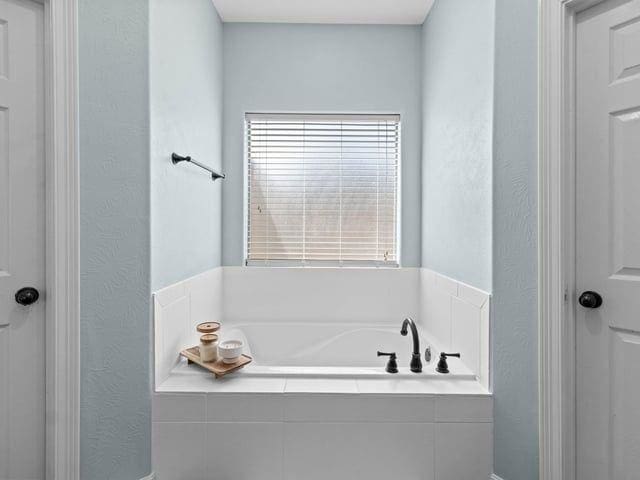 bathroom with a bath and a textured wall
