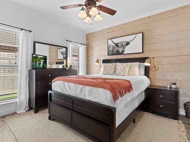 bedroom featuring multiple windows, crown molding, and a ceiling fan