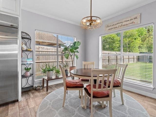 dining space featuring crown molding, a notable chandelier, and light wood-style floors