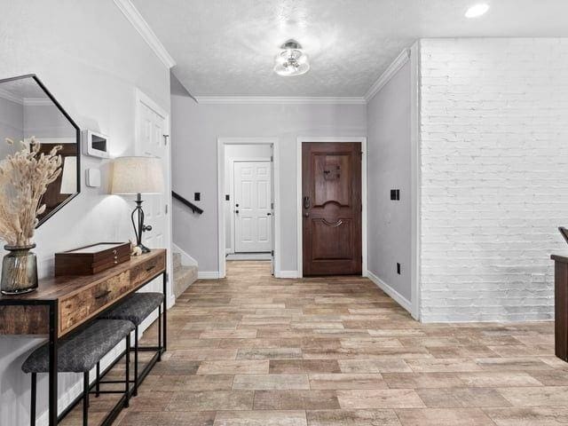 entryway with baseboards, stairs, light wood-type flooring, and crown molding