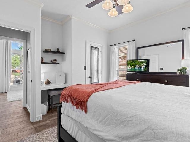 bedroom featuring baseboards, multiple windows, ornamental molding, and wood finished floors