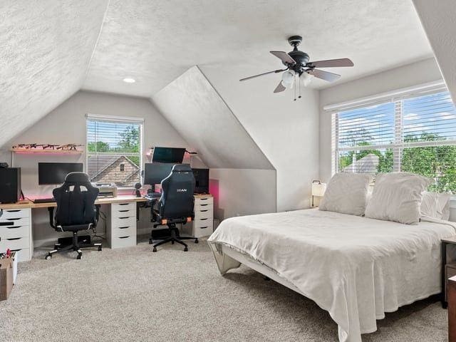bedroom with a ceiling fan, carpet flooring, vaulted ceiling, and a textured ceiling