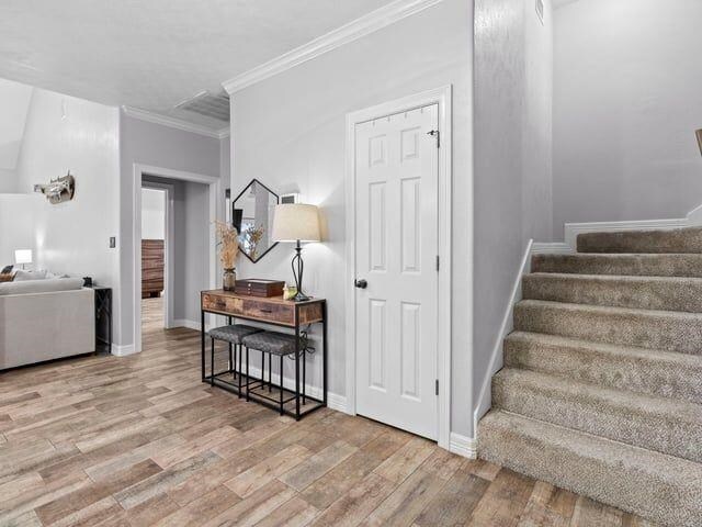 staircase featuring crown molding, baseboards, and wood finished floors