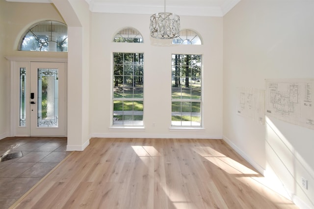 interior space featuring a chandelier, ornamental molding, light hardwood / wood-style floors, and a healthy amount of sunlight