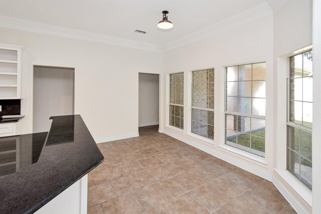 interior space with white cabinets, dark stone counters, and ornamental molding