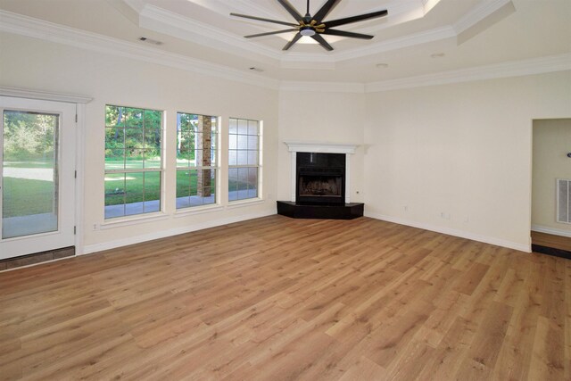 unfurnished living room with light wood-type flooring, a tray ceiling, ceiling fan, and ornamental molding