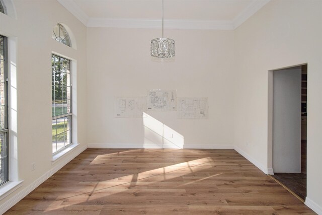 unfurnished dining area featuring hardwood / wood-style floors, an inviting chandelier, and crown molding