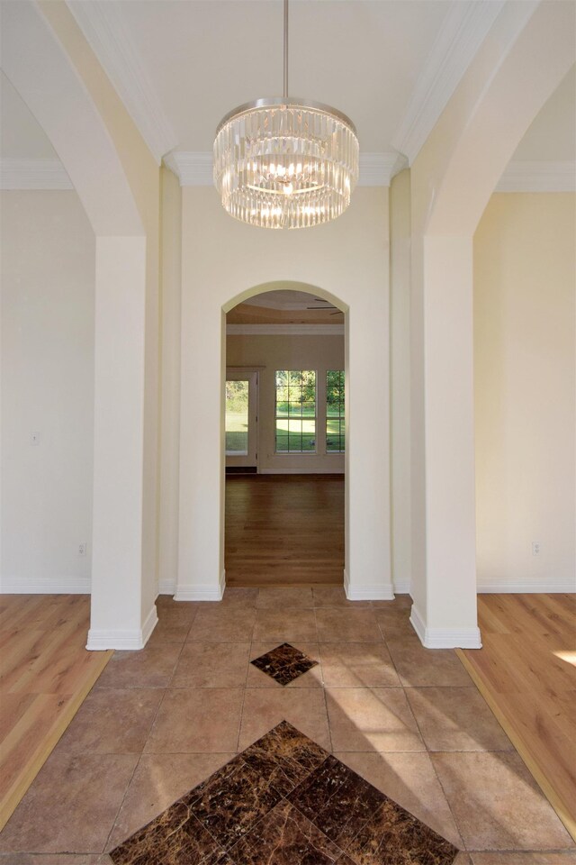 hall with hardwood / wood-style flooring, ornamental molding, and a notable chandelier