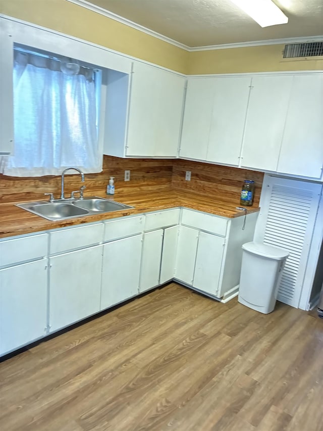 2515 Glenwood Dr, Port Arthur, TX 77642 - kitchen with ornamental molding, white cabinets, and light wood-style flooring