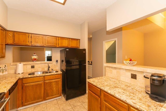 1620 Wellington Pl, Beaumont, TX 77706 - kitchen with freestanding refrigerator, a sink, backsplash, and brown cabinetry