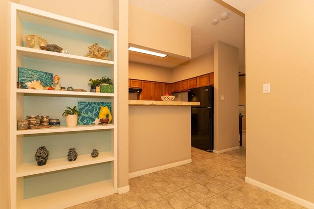 1620 Wellington Pl, Beaumont, TX 77706 - kitchen with open shelves, brown cabinetry, freestanding refrigerator, light countertops, and baseboards