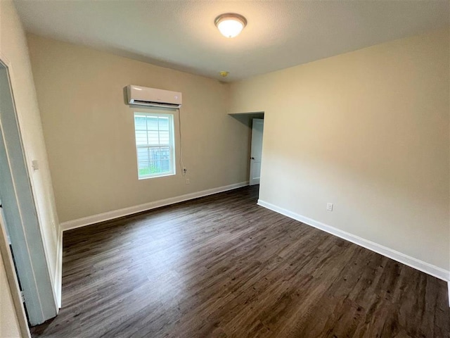 empty room with dark hardwood / wood-style floors and a wall mounted air conditioner