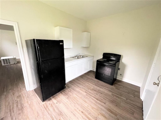 kitchen with sink, light hardwood / wood-style floors, white cabinetry, and black appliances