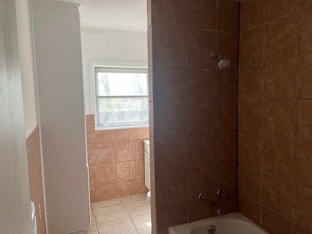 bathroom with tiled shower / bath, tile patterned flooring, toilet, a textured ceiling, and tile walls