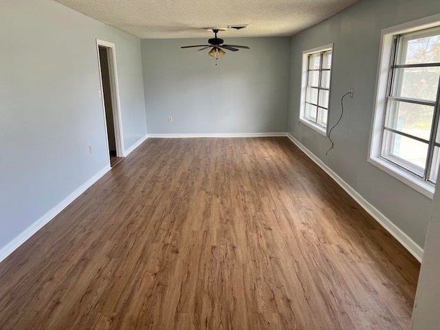 unfurnished room featuring a healthy amount of sunlight, wood-type flooring, and a textured ceiling