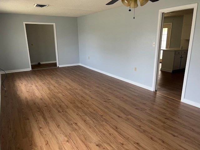 spare room with a textured ceiling, dark hardwood / wood-style flooring, and ceiling fan