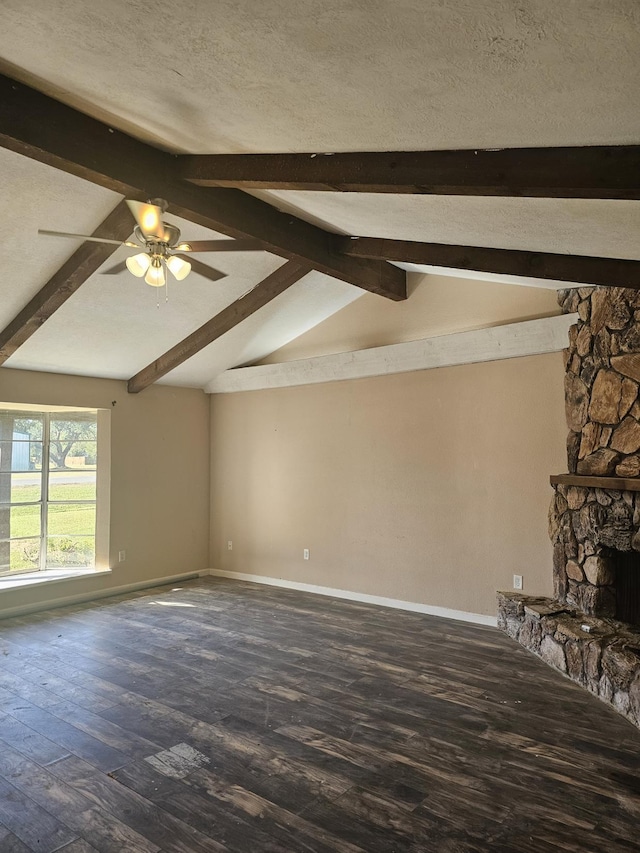 unfurnished living room featuring hardwood / wood-style floors, vaulted ceiling with beams, a stone fireplace, and a textured ceiling