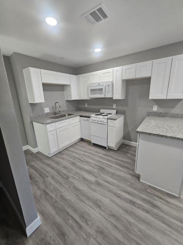 kitchen featuring white cabinetry, sink, light stone countertops, white appliances, and light wood-type flooring