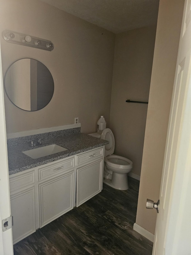 bathroom with hardwood / wood-style flooring, vanity, and toilet