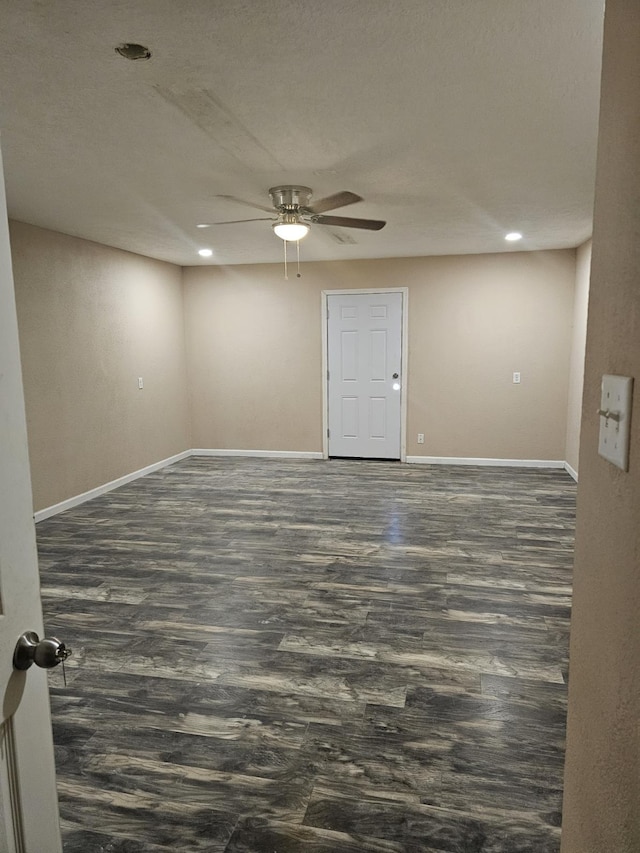 empty room with ceiling fan, a textured ceiling, and dark wood-type flooring