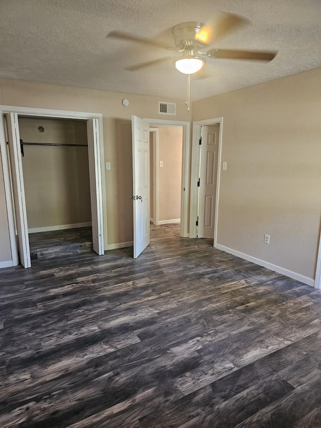 unfurnished bedroom featuring a textured ceiling, ceiling fan, a closet, and dark hardwood / wood-style floors