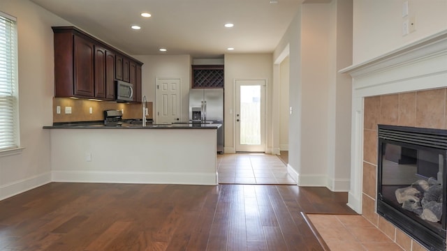 2650 Cedar Spgs, Port Arthur, TX 77640 - kitchen featuring appliances with stainless steel finishes, dark countertops, a peninsula, a tile fireplace, and recessed lighting