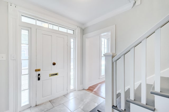 entryway with light tile patterned flooring and ornamental molding