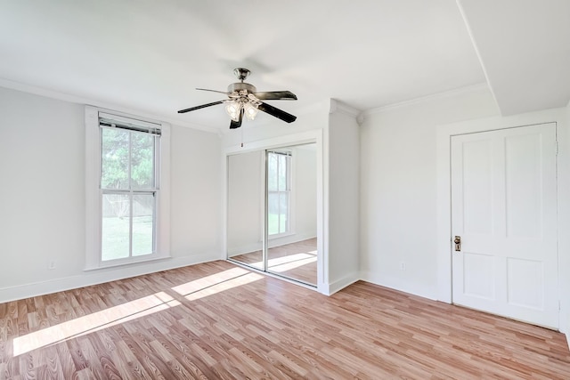 unfurnished bedroom featuring a closet, light hardwood / wood-style floors, ceiling fan, and ornamental molding