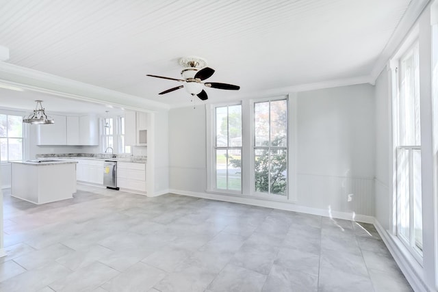 unfurnished living room with ceiling fan with notable chandelier, sink, and crown molding