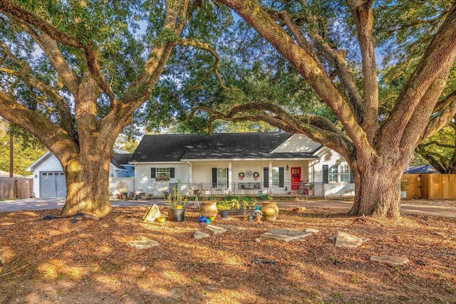 ranch-style house featuring covered porch, a garage, and an outbuilding