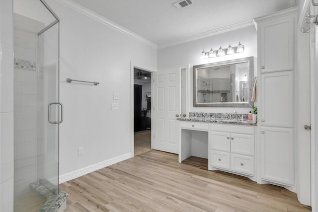 bathroom with ceiling fan, hardwood / wood-style floors, a shower with door, vanity, and ornamental molding