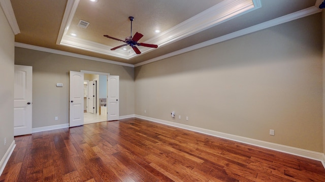 spare room featuring hardwood / wood-style floors, ceiling fan, a raised ceiling, and ornamental molding