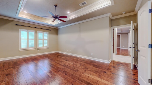 unfurnished room with a raised ceiling, crown molding, ceiling fan, and hardwood / wood-style flooring