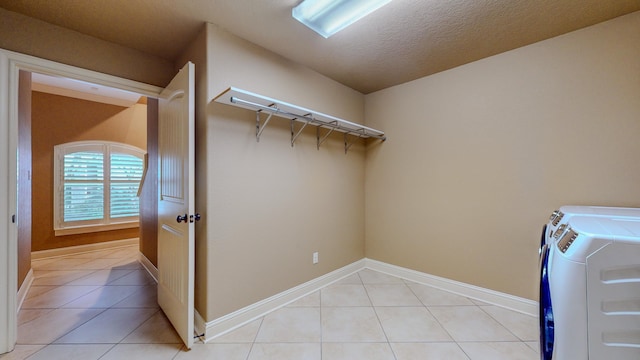 clothes washing area featuring washer and dryer, light tile patterned flooring, and a textured ceiling