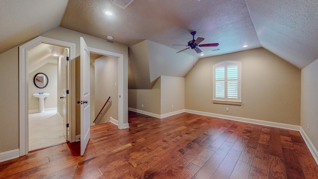 bonus room with a textured ceiling, dark hardwood / wood-style floors, vaulted ceiling, and ceiling fan