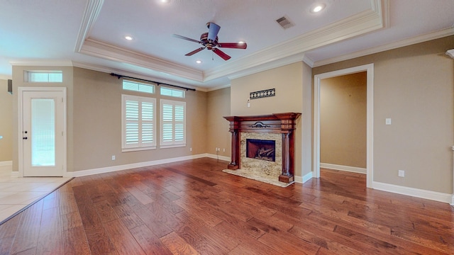 unfurnished living room with ornamental molding, a raised ceiling, ceiling fan, wood-type flooring, and a fireplace