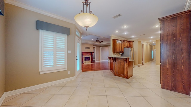 kitchen with stainless steel refrigerator, ceiling fan, kitchen peninsula, a breakfast bar, and ornamental molding