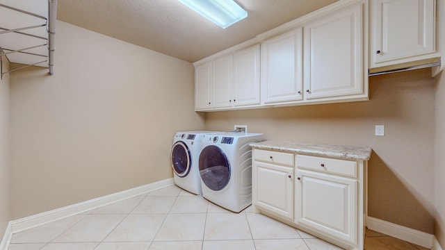 washroom featuring washer and clothes dryer, light tile patterned floors, cabinets, and a textured ceiling