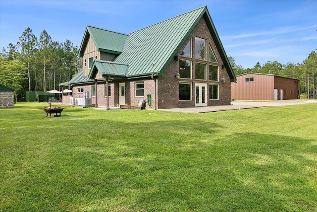 rear view of house featuring a garage, an outdoor structure, and a lawn