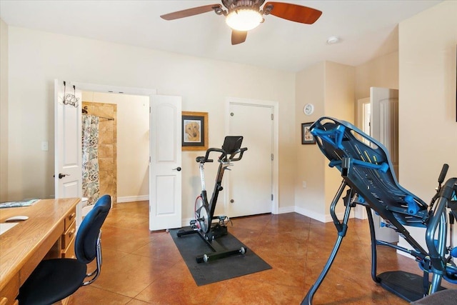 workout room featuring ceiling fan and dark tile patterned flooring