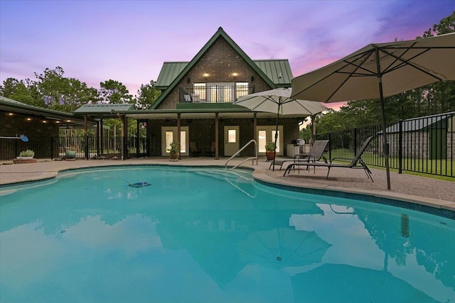 pool at dusk with a patio area