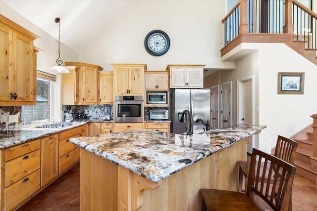 kitchen with light stone countertops, a center island, hanging light fixtures, decorative backsplash, and appliances with stainless steel finishes