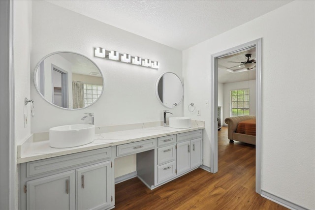6635 Griffing Rd, Beaumont, TX 77708 - ensuite bathroom featuring double vanity, a sink, a textured ceiling, and wood finished floors