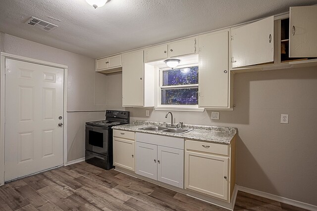 kitchen featuring white cabinets, sink, electric range, a textured ceiling, and light hardwood / wood-style floors