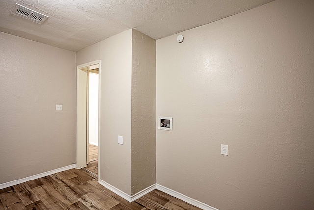 washroom with dark hardwood / wood-style floors, a textured ceiling, and hookup for a washing machine