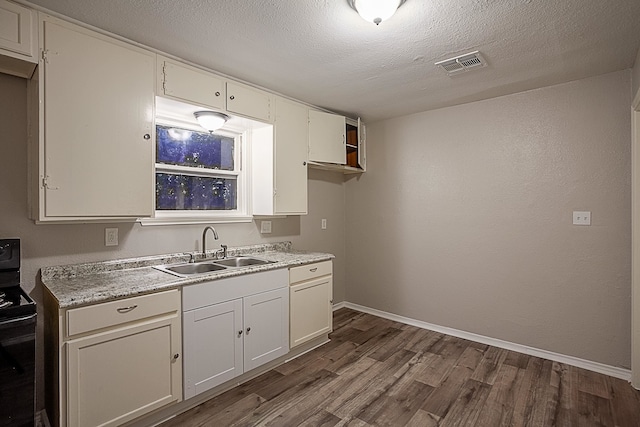 kitchen with white cabinetry, sink, dark wood-type flooring, black / electric stove, and a textured ceiling