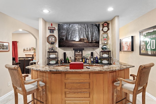 bar featuring light stone countertops and light tile patterned flooring